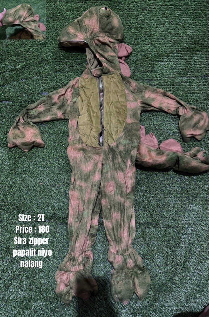 Dinosaur Costume Size 2T (Category: Babies & Kids Fashion) located in San Fernando. Submitted by InvisibleMe (Listing ID 1468709025, Image 1). Description: - Item: Green and pink dinosaur costume - Size: Toddler 2T - Features: Full bodysuit, attached hood with dinosaur eyes, soft spikes along the back, and claw details on sleeves and feet - Condition: Pre-loved, front zipper is broken and needs replacement - Perfect for: Budget-friendly dress-up,