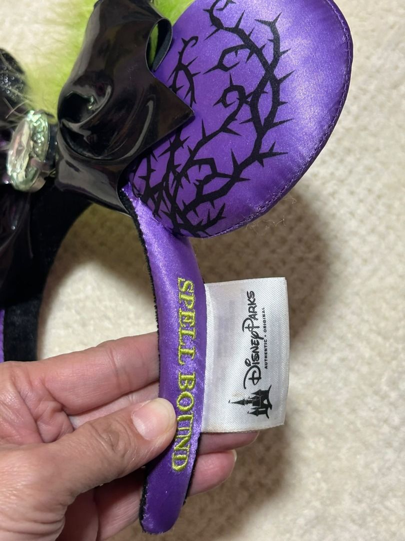Disney Maleficent Spell Headband (Category: Hair Accessories) located in Las Pinas. Submitted by whatzupriley (Listing ID 1468555397, Image 1). Description: - Authentic Disney Parks Spell Bound collection Maleficent headband - Purple satin ears with striking black thorn print - Black patent bow featuring a large crystal centerpiece - Detailed with small black horns and green feather accents - Comfortable purple headband with original Disney Parks