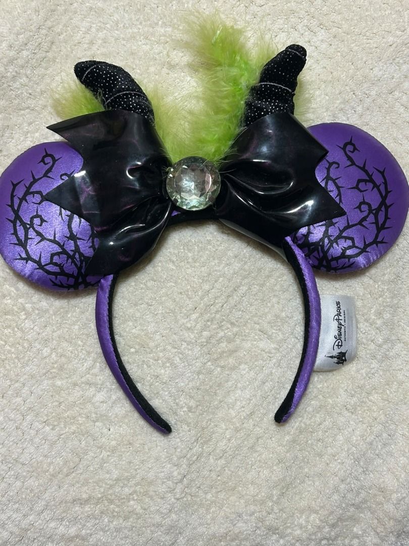 Disney Maleficent Spell Headband (Category: Hair Accessories) located in Las Pinas. Submitted by whatzupriley (Listing ID 1468555397, Image 3). Description: - Authentic Disney Parks Spell Bound collection Maleficent headband - Purple satin ears with striking black thorn print - Black patent bow featuring a large crystal centerpiece - Detailed with small black horns and green feather accents - Comfortable purple headband with original Disney Parks