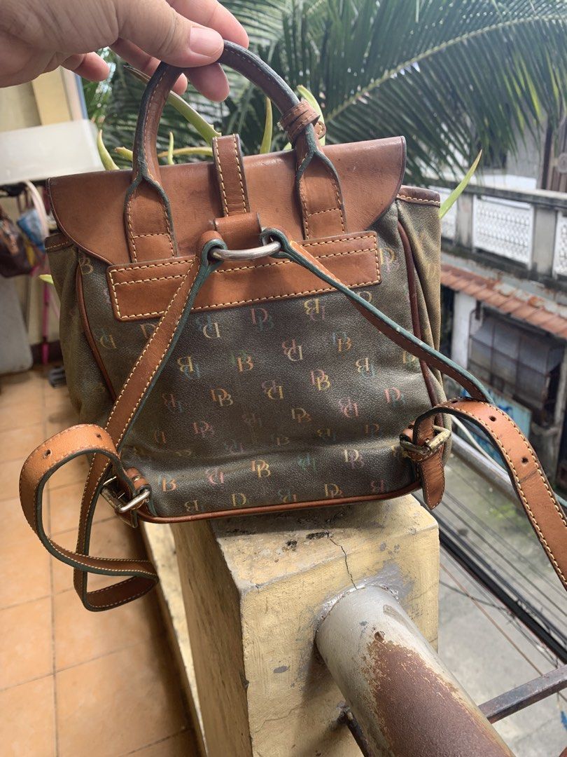 Dooney & Bourke Monogram Mini Backpack (Category: Backpacks) located in Pasig City. Submitted by cool.itshara (Listing ID 1468551212, Image 3). Description: - Brand: Dooney & Bourke - Style: Mini backpack - Color: Olive green monogram print with brown leather accents - Features: Flap top, top handle, adjustable shoulder straps, and cute heart-shaped front charm - Hardware: Durable metal accents - Condition: Excellent / Well-maintained - Perfect f