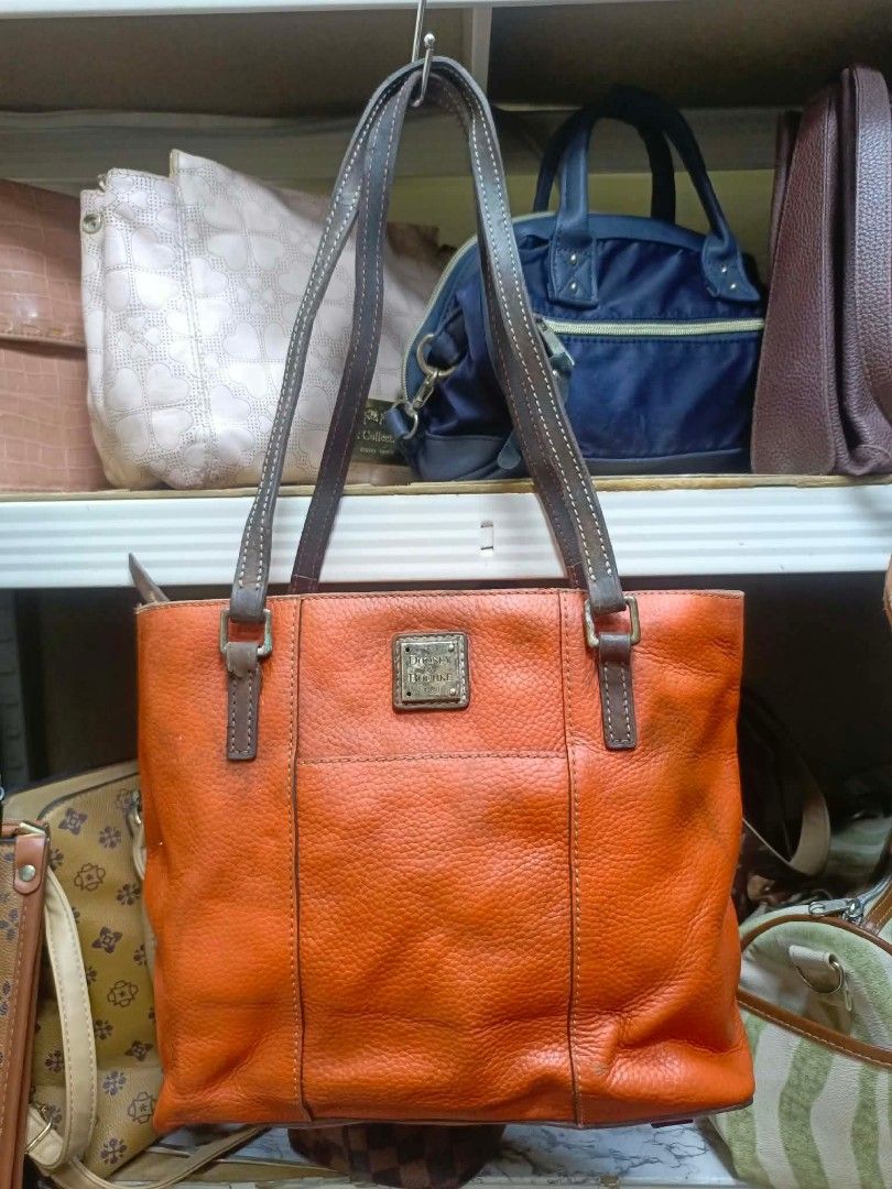 Dooney & Bourke Orange Leather Tote Bag (Category: Luxury Bags & Wallets) located in Manila. Submitted by dei03_diz (Listing ID 1468543278, Image 1). Description: - Brand/Model: Dooney & Bourke Tote Bag - Color: Bright orange pebble leather with vibrant red interior - Hardware: Gold-tone metal hardware with front exterior logo plaque - Straps: Comfortable double shoulder straps - Closure: Secure top zip closure - Interior: Red fabric lining featu