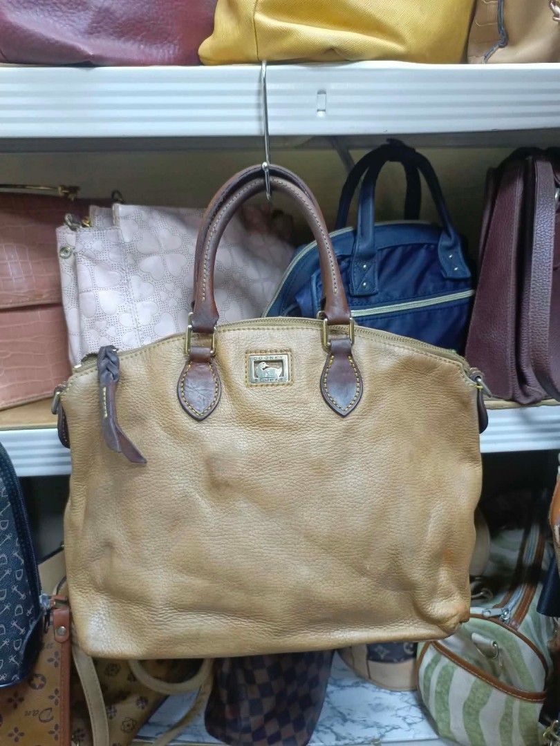 Dooney & Bourke Tan Leather Shoulder Bag (Category: Luxury Bags & Wallets) located in Manila. Submitted by dei03_diz (Listing ID 1468543956, Image 1). Description: - Brand: Dooney & Bourke - Material: Tan pebbled leather with brown leather trim - Hardware: Iconic metal duck logo plaque on front, Riri zipper closure - Interior: Pink checkered fabric lining with a zipper pocket and brand tag - Condition: Shows natural wear on the leather and slight