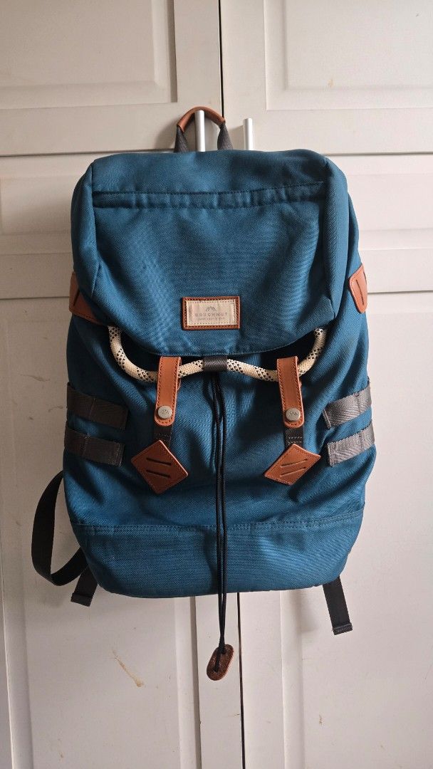 Doughnut Blue Canvas Backpack with Brown Leather Accents (Category: Backpacks) located in Mandaluyong City. Submitted by ohayouclub (Listing ID 1468529268, Image 1). Description: - Brand/Model: Doughnut Backpack in Dark Teal Blue - Material & Accents: Durable canvas with brown leather and rope details - Closure: Drawstring main closure with secure buckle straps - Comfort & Carry: Padded shoulder straps equipped with metal D-rings - Storage: Conve