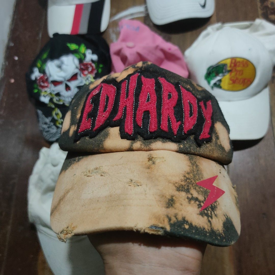 Ed Hardy Acid Wash Distressed Trucker Cap (Category: Caps & Hats) located in Taguig. Submitted by actualizeboutique (Listing ID 1468524754, Image 1). Description: - Brand: Ed Hardy - Style: Trucker cap with distressed acid wash finish and heavy wear on the brim - Details: Bright red embroidered front logo and small pink lightning bolt graphic on the right side - Back: Black mesh panel with adjustable snapback closure - Branding: Embroidered scrip