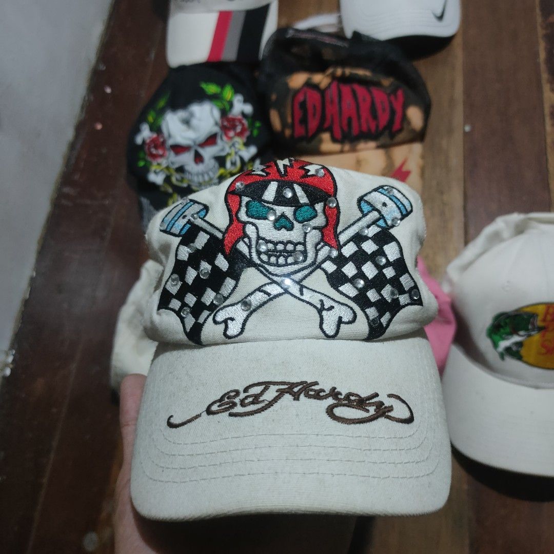 Ed Hardy Trucker Hat White Skull Racing Flags (Category: Caps & Hats) located in Taguig. Submitted by actualizeboutique (Listing ID 1468524511, Image 1). Description: - Brand: Ed Hardy - Style: White trucker hat with adjustable plastic snapback closure - Design: Rhinestone-embellished skull wearing a racing helmet, checkered flags, and pistons, with embroidered Ed Hardy script on the brim - Material/Backing: White mesh back panels - Condition: Go