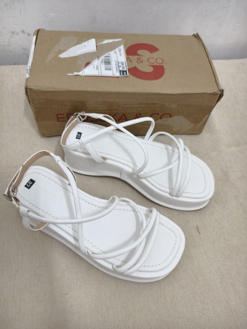 Erosska & Co. White Platform Sandals Size 37 (Category: Sandals) located in Angeles City. Submitted by measaliman02351 (Listing ID 1468504611, Image 1). Description: - Brand: Erosska & Co. - Size: 37 (marked on insole) - Color: White - Style: Strappy platform sandals with thin criss-cross straps and ankle buckle closure - Heel: Chunky wedge heel and thick sole - Inclusions: Comes with original branded shoe box - Condition: Excellent/Ready to wear