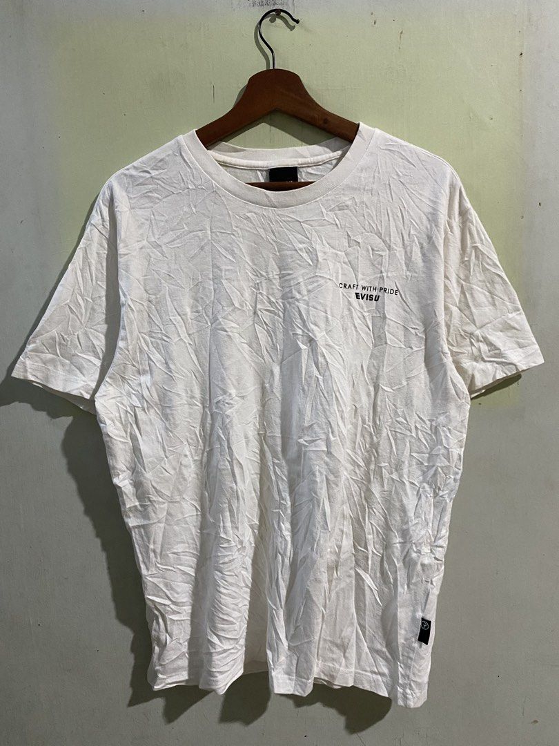 Evisu Craft With Pride White T-shirt (Category: Tshirts & Polo Shirts ) located in Pandi. Submitted by nasya_thrift_collection2023 (Listing ID 1468594959, Image 1). Description: - Brand: Evisu - Color: White with black front chest text ("Craft with Pride") - Design: Large red Evisu graphic with typography on the back - Details: Black neck tag with white lettering, standard crew neck, and short sleeves - Authenticity: Korean wash tag with QR code 