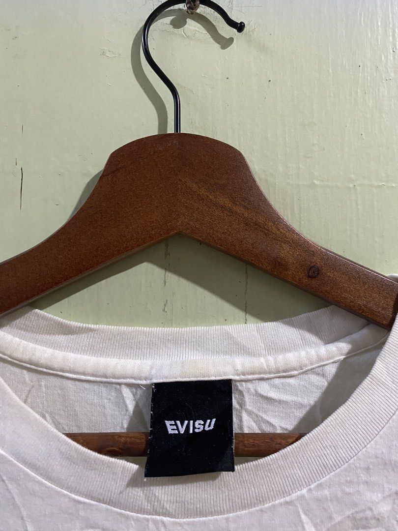 Evisu Craft With Pride White T-shirt (Category: Tshirts & Polo Shirts ) located in Pandi. Submitted by nasya_thrift_collection2023 (Listing ID 1468594959, Image 3). Description: - Brand: Evisu - Color: White with black front chest text ("Craft with Pride") - Design: Large red Evisu graphic with typography on the back - Details: Black neck tag with white lettering, standard crew neck, and short sleeves - Authenticity: Korean wash tag with QR code 