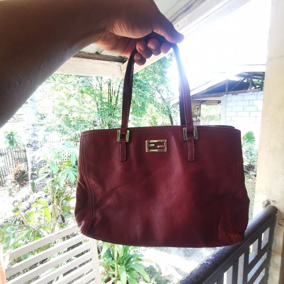 Fendi Red Leather Tote Bag (Category: Tote Bags) located in Davao. Submitted by dmp1993 (Listing ID 1468581445, Image 1). Description: Deep red leather tote bag from Fendi. Gold-tone hardware with the Fendi logo plate on the front. Double top handles. Interior lined in fabric with zipper pocket, Fendi metal plaque, and authenticity tag. Made in Italy. Zipper pull engraved with Fendi branding..