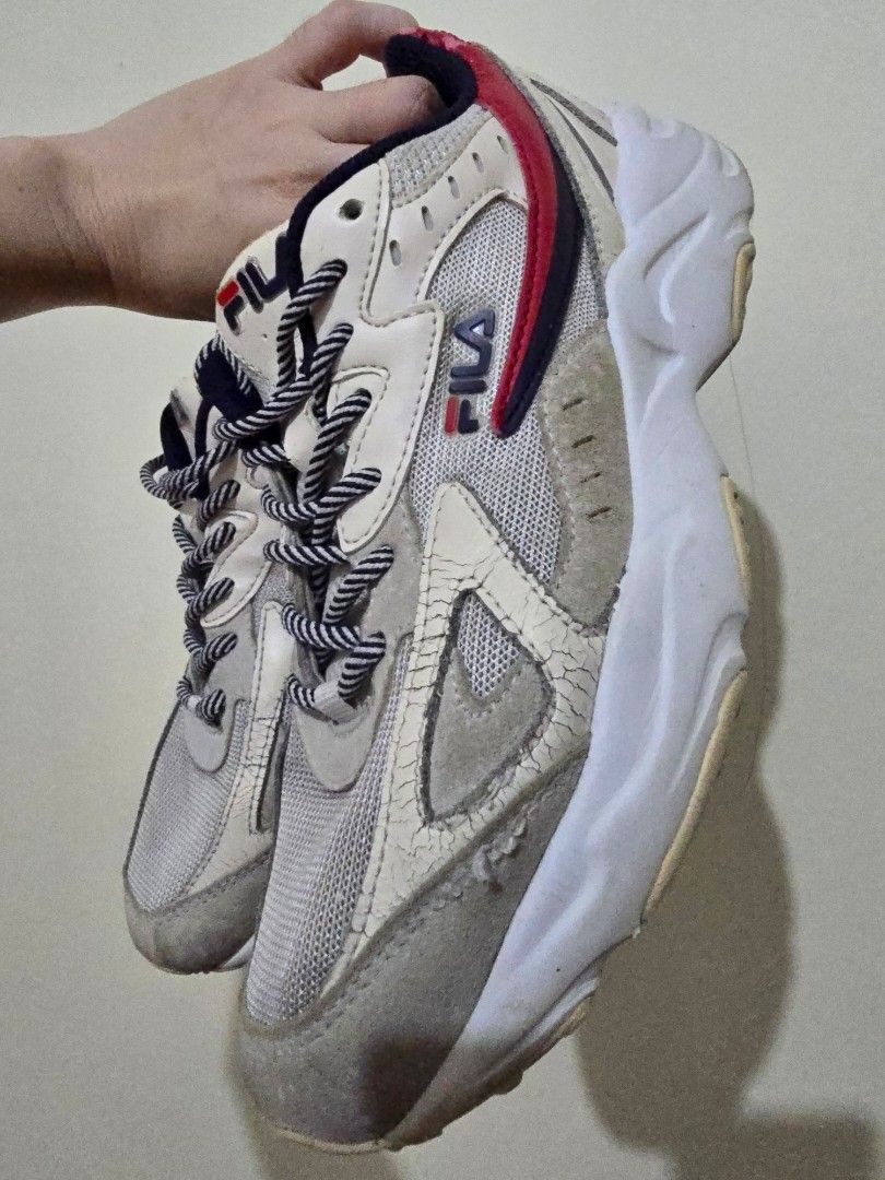 Fila chunky sneakers (Category: Sneakers) located in Makati City. Submitted by gentletree.4b536a (Listing ID 1468531553, Image 2). Description: - Brand: Fila - Color: White and grey with navy and red accents - Materials: Mesh panels, suede overlays, and thick rubber soles - Details: Branded tongues and black/white patterned rope laces - Condition: Noticeable creasing on the leather tongue and toe box, with general wear and scuffs on the upper sol