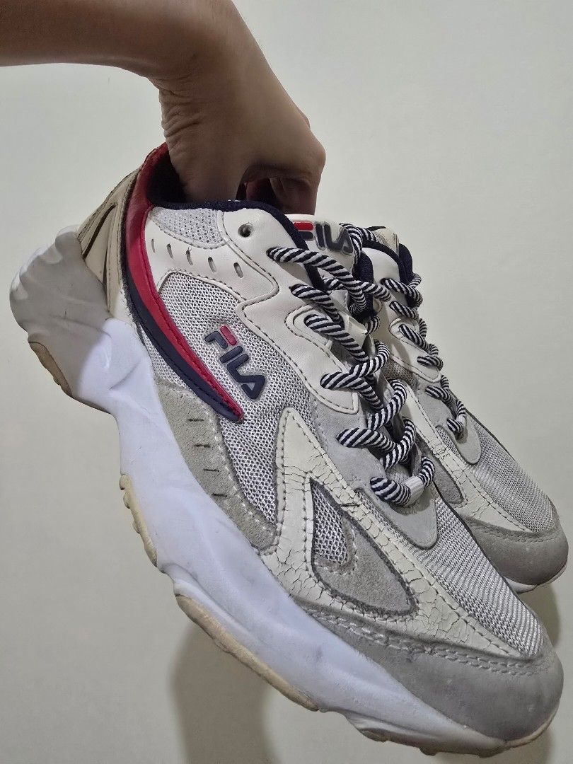 Fila chunky sneakers (Category: Sneakers) located in Makati City. Submitted by gentletree.4b536a (Listing ID 1468531553, Image 3). Description: - Brand: Fila - Color: White and grey with navy and red accents - Materials: Mesh panels, suede overlays, and thick rubber soles - Details: Branded tongues and black/white patterned rope laces - Condition: Noticeable creasing on the leather tongue and toe box, with general wear and scuffs on the upper sol