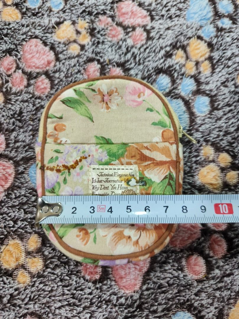 Floral pattern fabric coin purse with zip closure (Category: Purses & Pouches) located in San Leonardo. Submitted by burgossanleonardo.12345 (Listing ID 1468647735, Image 2). Description: - Vintage floral fabric coin purse in earthy beige, green, and brown tones - Measures approximately 11 cm tall for a compact, everyday fit - Secure top zip closure to keep your items safe - Front slip pocket with a charming sewn-on label - Fully lined with a pre