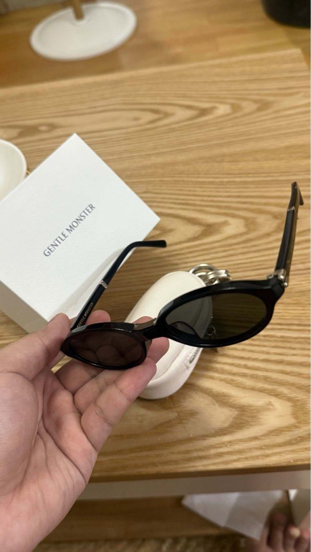 Foldable Gentle Monster Sunglasses with pouch (Category: Sunglasses & Eyewear) located in Paranaque City. Submitted by atbp2022 (Listing ID 1468574248, Image 2). Description: - Brand: Gentle Monster - Style: Ivy, Trendy oval shape with black frames and dark lenses - Condition: brand new, worn only once for a quick photo - Inclusions: Original white protective case with keyring attachment and white branded packaging box - Perfect for daily wear an