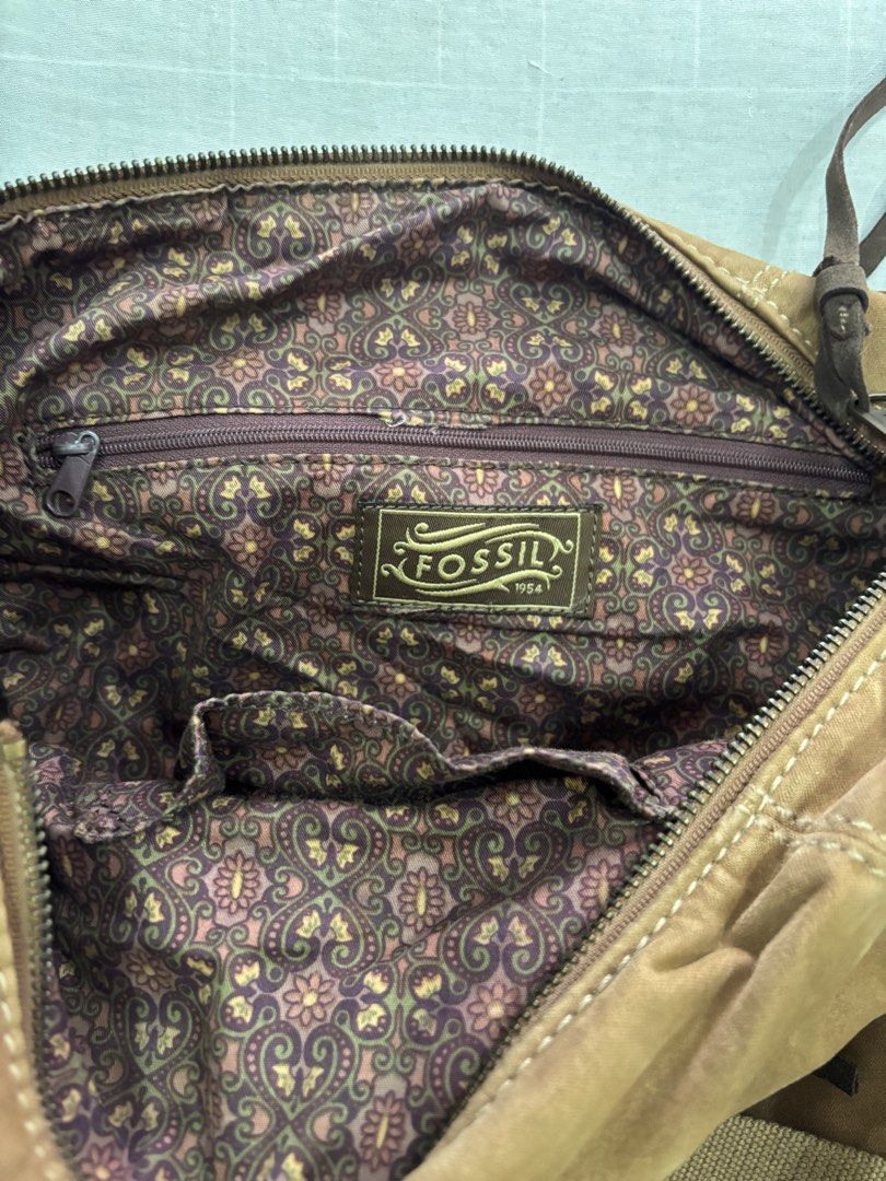 Fossil Brown Canvas Crossbody Shoulder Bag (Category: Cross-body Bags) located in Floridablanca. Submitted by jmvbautista (Listing ID 1468542686, Image 3). Description: - Brand: Fossil - Material: Durable brown canvas with premium leather trim and antique bronze hardware - Versatile Carry: Includes dual top handles and a detachable, adjustable crossbody strap - Exterior Storage: Dual front zippered pockets, front slip pocket, and iconic Fossil 19