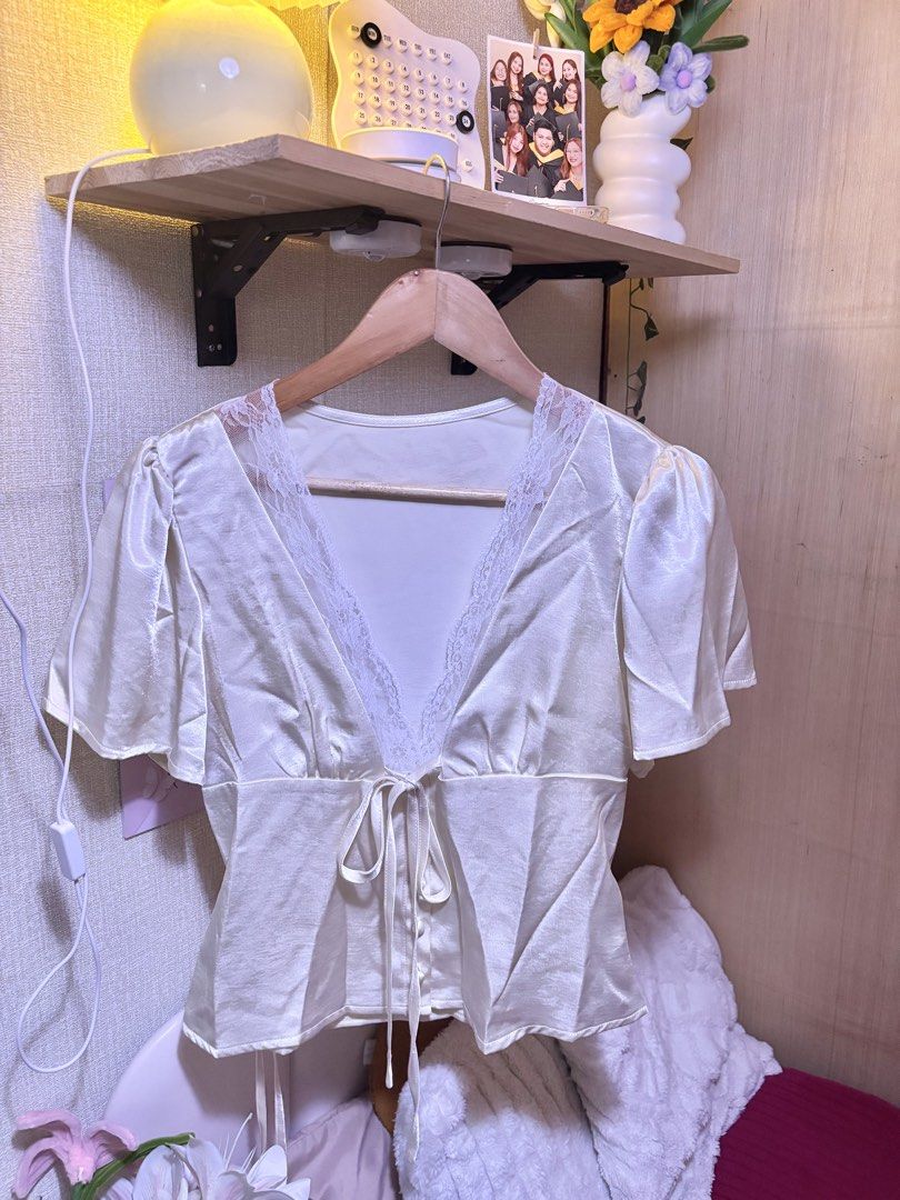 Glamine White Lace Satin Tie-Front Top (Category: Blouses) located in Manila. Submitted by joe_fashion1234 (Listing ID 1468584829, Image 1). Description: - Brand: Glamine - Color: Cream with white lace trim - Material: Lightweight satin with a slight sheen - Design: Deep V-neckline, front tie closure, decorative pearl-style buttons, and short puff sleeves - Versatile style: Ideal for daytime events, brunch, or casual outings - Easy to style: Look