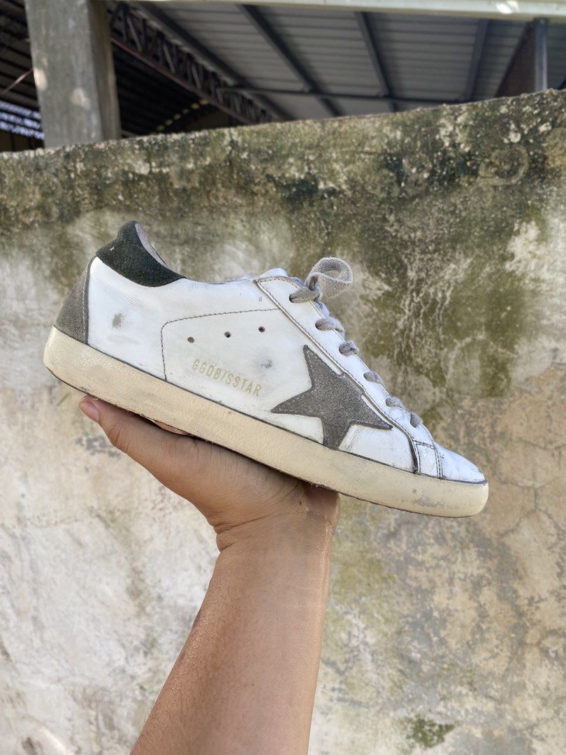 Golden Goose Superstar White Sneakers (Category: Sneakers) located in Iloilo. Submitted by resellmpg (Listing ID 1468558189, Image 1). Description: - Brand: Golden Goose - Color: White leather with grey suede star and dark green heel tab - Design: Signature distressed finish on midsole and upper - Details: Grey laces, classic low-top silhouette, white logo lettering on heel - Mode of Payment: BPI, GCash, or COD available - Shipping: Via LBC or sa