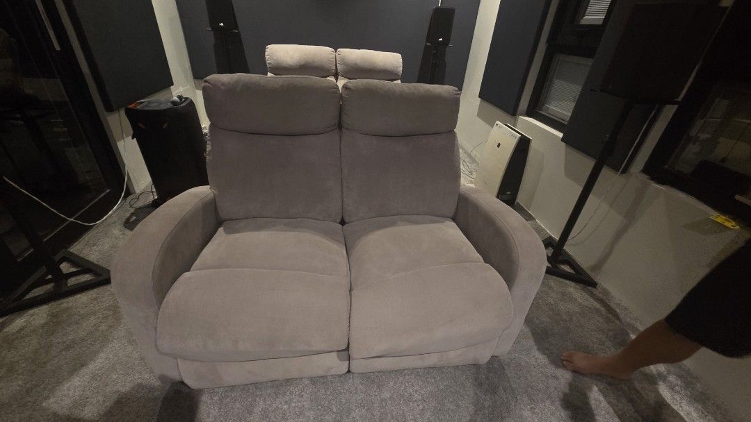 Grey Two-Seater Recliner Sofa (Category: Sofas) located in Pasig City. Submitted by annsvault (Listing ID 1468603087, Image 2). Description: - Color: Grey - Seating: Comfortably fits 2 people - Support: Plush cushions, padded armrests, and high backs for head support - Design: Soft upholstery with clean edge stitching - Frame: Sturdy and durable build - Size: Compact, ideal for small living rooms or media spaces.