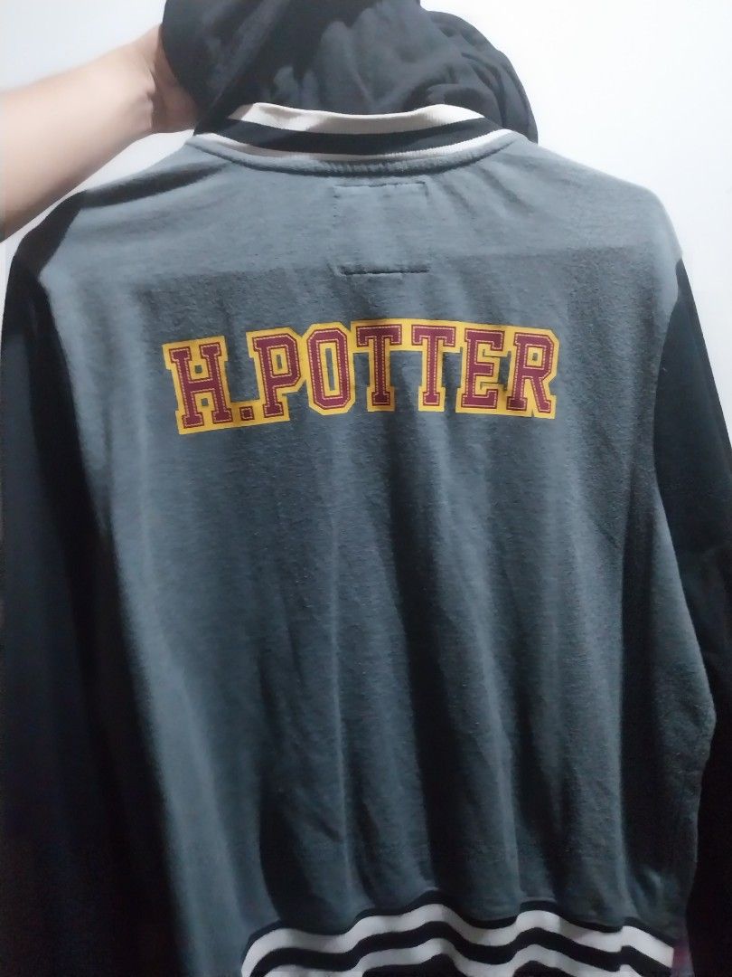 Harry Potter Gryffindor Varsity Jacket official merch (Category: Coats, Jackets and Outerwear) located in Manila. Submitted by j.dlh (Listing ID 1468662836, Image 2). Description: - Official Harry Potter Gryffindor varsity jacket - Color: Grey and black with an attached black hood - Embroidered Gryffindor crest on the chest - Vertical 'POTTER' lettering on the back in yellow and maroon - Snap button front closure - Striped ribbed collar, cuffs, a