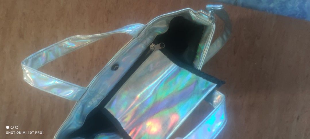 Holographic Metallic Tote Bag with Shoulder Strap (Category: Tote Bags) located in Cavite. Submitted by Combiishop (Listing ID 1468557703, Image 2). Description: - Eye-catching shiny holographic metallic finish that shifts color in the light - Versatile design with short carry handles and a detachable long shoulder strap - Secure top snap button closure with sleek silver hardware - Spacious main compartment lined in black fabric - Convenient zipp