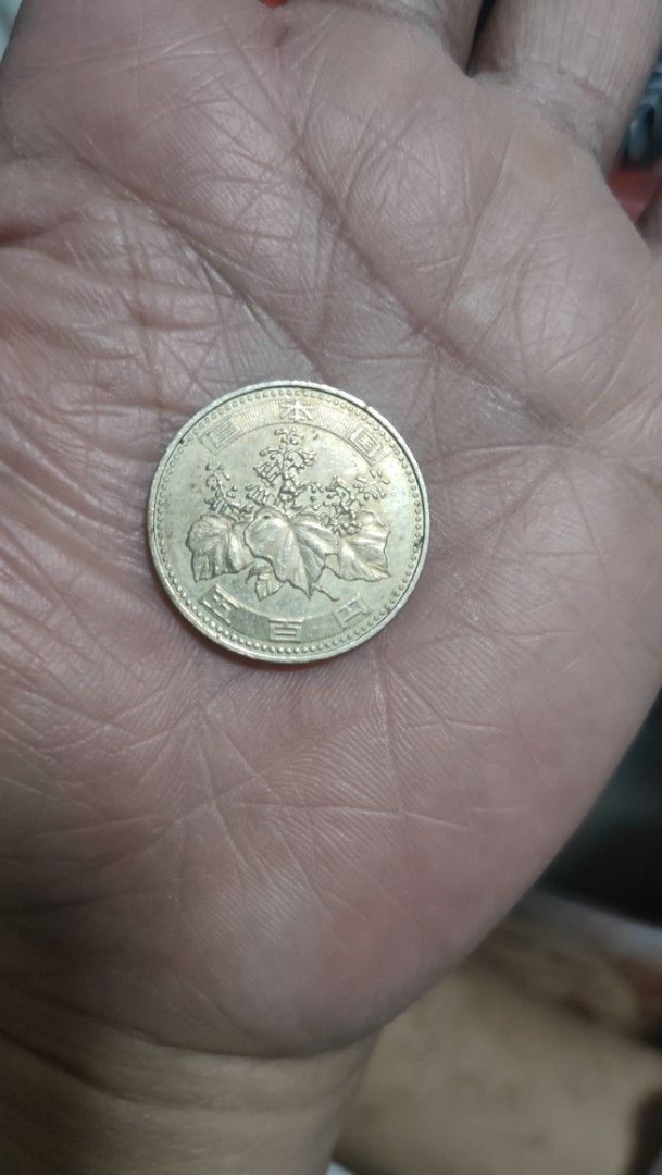 Japanese 500 Yen Coin (Category: Currency) located in Caloocan City. Submitted by joshuadyogi0122 (Listing ID 1468507084, Image 2). Description: Japanese 500 yen coin resting in an open palm. Face shows 500 numerals and Japanese characters. Reverse displays a paulownia plant design with leaves and flowers. Standard currency size, metallic finish with minor signs of handling. Great piece for coin collectors or anyone needing Japanese currency..