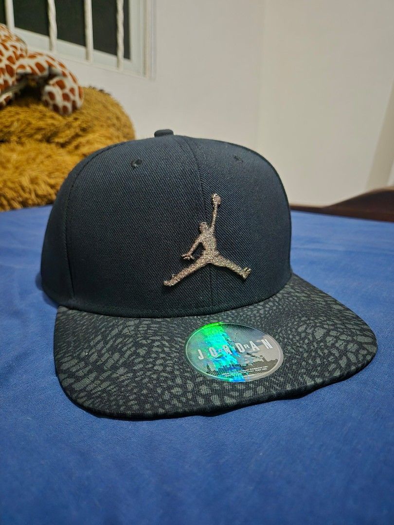 Jordan Jumpman Strapback Cap Black Bronze Elephant Bill (Category: Caps & Hats) located in Pasig City. Submitted by lordcajayon (Listing ID 1468679629, Image 1). Description: - Brand: Jordan - Color: Black with dark grey elephant print brim - Logo: Textured gold Jumpman logo on the front - Authenticity: Includes official hologram sticker on the brim - Fit: Adjustable strap at the back with a metal clasp and small Jumpman tag - Details: Inside tap
