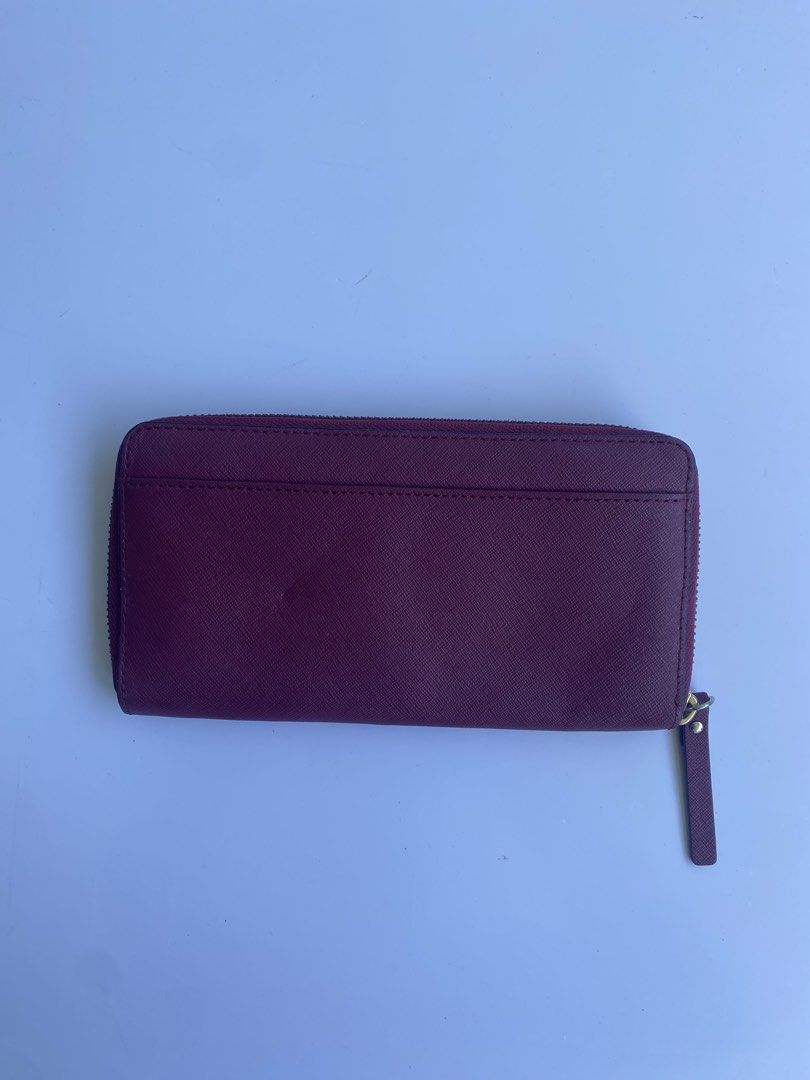 Kate Spade Burgundy Zip Around Wallet (Category: Wallets & Card holders) located in Cavite. Submitted by benta_bounce (Listing ID 1468555854, Image 2). Description: - Brand: Kate Spade - Style: Zip-around wallet - Material: Durable Saffiano leather - Color: Rich burgundy - Hardware: Gold-tone with matching leather zip pull - Exterior: Convenient back slip pocket - Branding: Signature spade logo stud on the front.