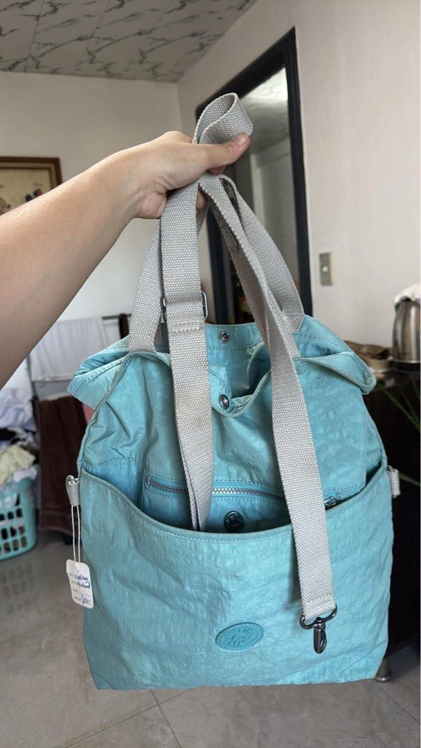 Kipling tote bag shoulder or backpack (Category: Tote Bags) located in Quezon City. Submitted by auspv_collections (Listing ID 1468619769, Image 1). Description: - Brand: Kipling - Color: Light Blue - Material: Signature crinkled nylon - Straps: Grey adjustable webbing straps - Pockets: Exterior front zip pocket and interior zippered pocket - Compartment: Spacious main compartment with patterned fabric lining - Details: Iconic circular Kipling lo