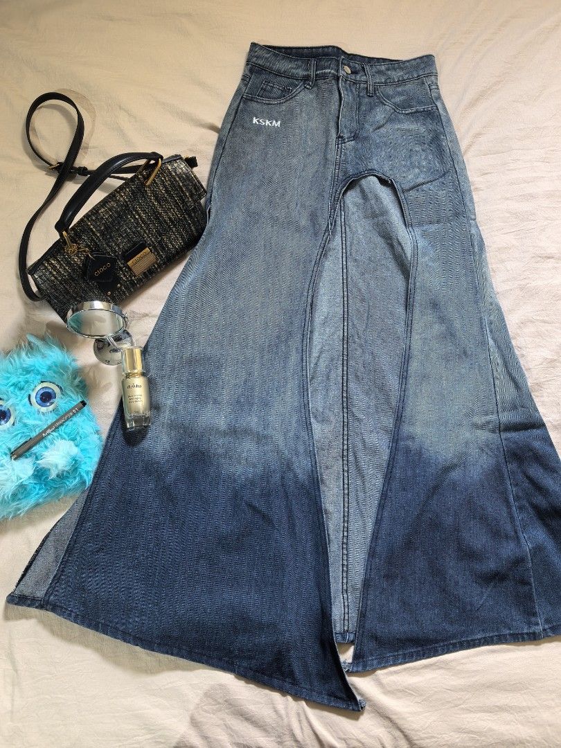 KSKM Denim Skirt Split Front Dip Dye (Category: Skirts) located in Tacloban City. Submitted by thead.declutters (Listing ID 1468643231, Image 1). Description: - Brand: KSKM - Style: High-waisted denim skirt with a bold center front split and asymmetrical layered panel - Color/Wash: Washed blue with a heavy dip-dye ombre bottom - Details: Standard belt loops, front and back pockets, and white brand lettering stamped near the right pocket - Fit: Fl