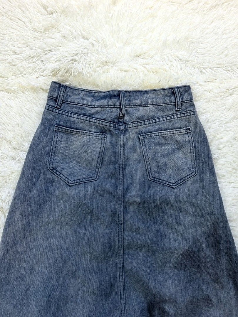 KSKM Denim Skirt Split Front Dip Dye (Category: Skirts) located in Tacloban City. Submitted by thead.declutters (Listing ID 1468643231, Image 3). Description: - Brand: KSKM - Style: High-waisted denim skirt with a bold center front split and asymmetrical layered panel - Color/Wash: Washed blue with a heavy dip-dye ombre bottom - Details: Standard belt loops, front and back pockets, and white brand lettering stamped near the right pocket - Fit: Fl