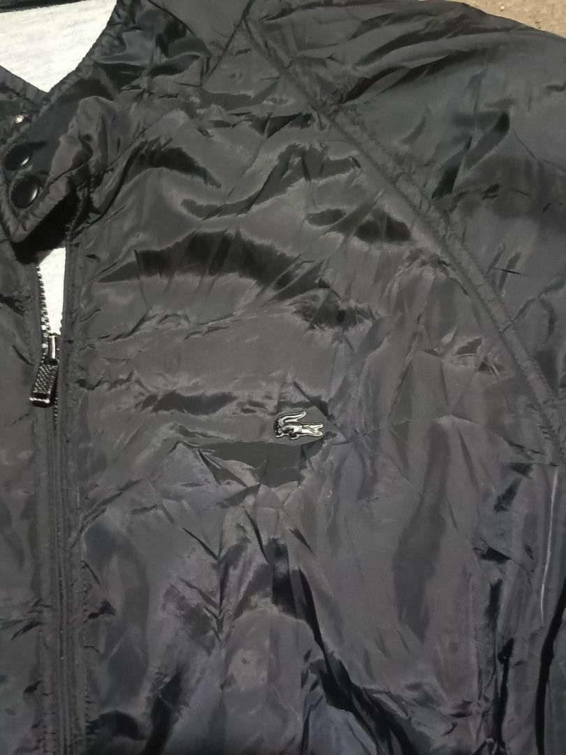 Lacoste Black Windbreaker Jacket Size 50/4 (Category: Coats, Jackets and Outerwear) located in City of Isabela. Submitted by warmbird.d06e6f (Listing ID 1468510350, Image 2). Description: - 100% Authentic Lacoste jacket in classic black - Size: 50/4 (Refer to tag) - Material: Durable nylon outer shell with soft grey polyester lining - Design: Full zip front, stand collar with snap button closure, and ribbed cuffs and hem - Pockets: Dual secure zi