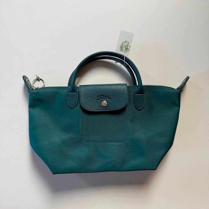 LC handbag (Category: Purses & Pouches) located in Manila. Submitted by mamapards17 (Listing ID 1468591279, Image 1). Description: teal-colored Longchamp Le Pliage-style short-handle handbag with a leather flap and snap closure..