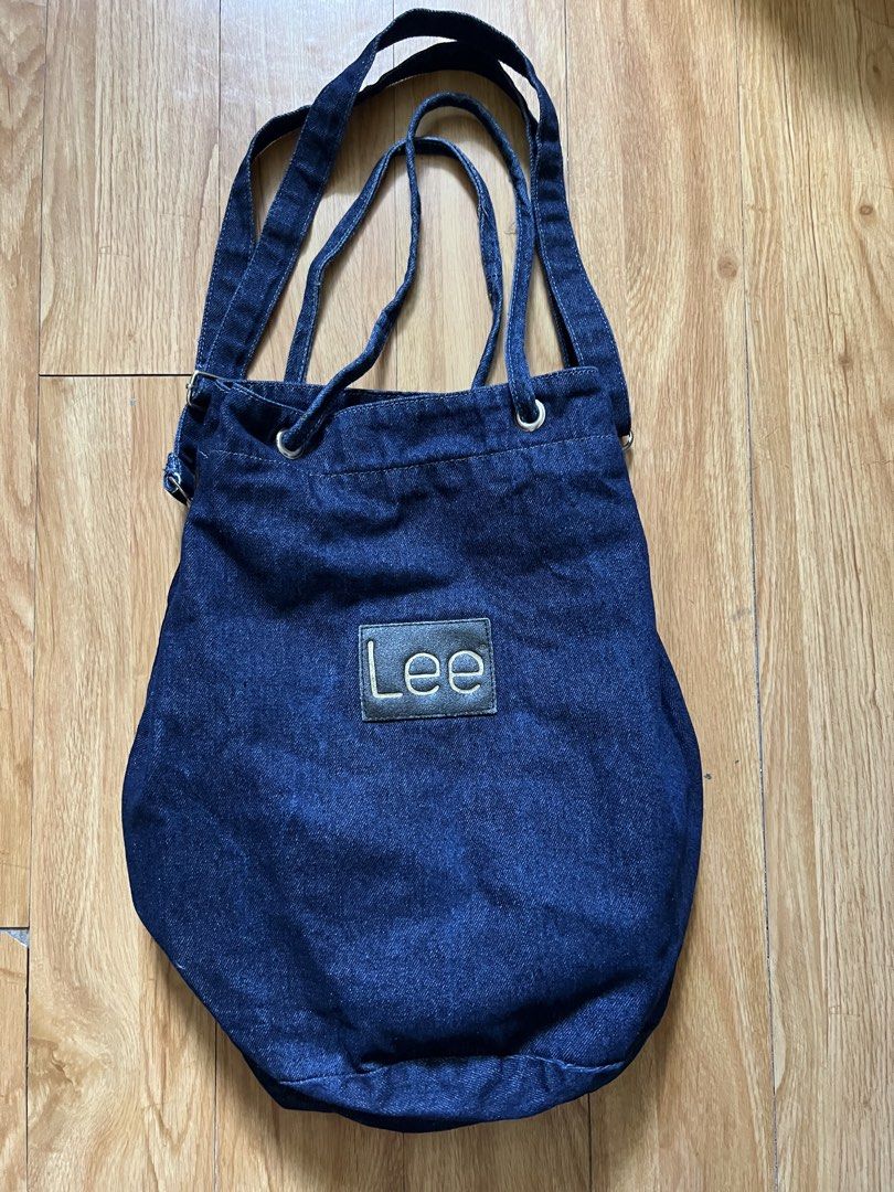 Lee Denim Tote Bag (Category: Tote Bags) located in Rizal. Submitted by s0apandglory (Listing ID 1468560647, Image 1). Description: - Brand: Lee - Material: Dark wash denim with black leather logo patch - Closure: Top drawstring with metal grommets - Straps: Dual shoulder straps plus adjustable side straps - Interior: Red and white striped fabric lining - Style: Casual, roomy everyday carryall - Condition: Excellent / Well-maintained - Shipping: 