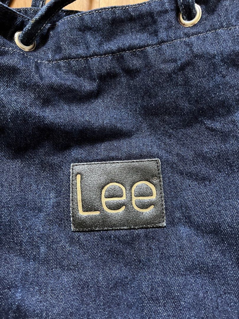Lee Denim Tote Bag (Category: Tote Bags) located in Rizal. Submitted by s0apandglory (Listing ID 1468560647, Image 3). Description: - Brand: Lee - Material: Dark wash denim with black leather logo patch - Closure: Top drawstring with metal grommets - Straps: Dual shoulder straps plus adjustable side straps - Interior: Red and white striped fabric lining - Style: Casual, roomy everyday carryall - Condition: Excellent / Well-maintained - Shipping: 