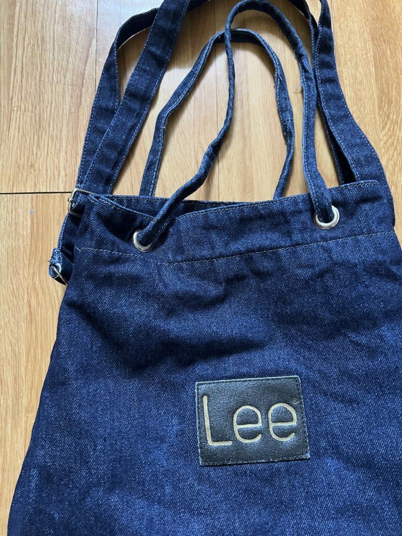 Lee Denim Tote Bag (Category: Tote Bags) located in Rizal. Submitted by s0apandglory (Listing ID 1468560647, Image 2). Description: - Brand: Lee - Material: Dark wash denim with black leather logo patch - Closure: Top drawstring with metal grommets - Straps: Dual shoulder straps plus adjustable side straps - Interior: Red and white striped fabric lining - Style: Casual, roomy everyday carryall - Condition: Excellent / Well-maintained - Shipping: 