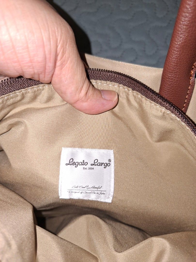 Legato Largo Beige Tote Bag with Shoulder Strap (Category: Tote Bags) located in Pasig City. Submitted by bolddeer_2ab1c6 (Listing ID 1468541305, Image 3). Description: - Brand: Legato Largo (Est. 2004) - Material: Durable beige nylon with brown faux leather handles - Hardware: Premium gold-tone hardware with protective plastic still on the zipper pull - Compartments: Main compartment with a convenient center zip divider plus interior pockets - S