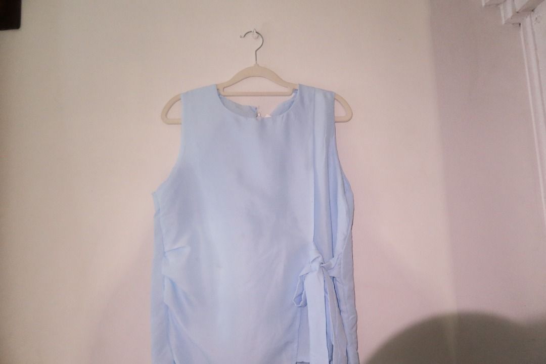 Light Blue Sleeveless Side-Tie Blouse (Category: Sleeveless) located in Manila. Submitted by imama23 (Listing ID 1468538871, Image 2). Description: - Color: Light blue - Style: Sleeveless top with round neckline - Design: Trendy asymmetrical hem and side tie wrap detail - Fabric: Smooth, lightweight, and flowy material Condition: 8/10 (has a minor dirt stain not noticeable) Size: S Location: Manila (Near Taft) Shipping - Payment first before ship