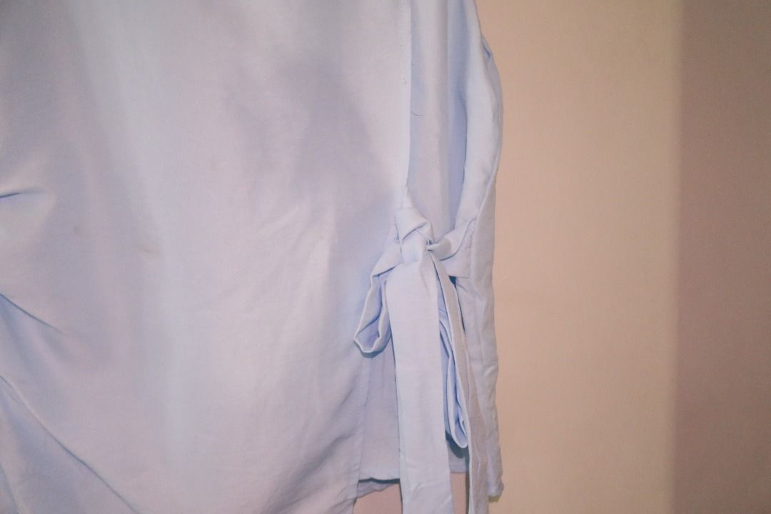 Light Blue Sleeveless Side-Tie Blouse (Category: Sleeveless) located in Manila. Submitted by imama23 (Listing ID 1468538871, Image 3). Description: - Color: Light blue - Style: Sleeveless top with round neckline - Design: Trendy asymmetrical hem and side tie wrap detail - Fabric: Smooth, lightweight, and flowy material Condition: 8/10 (has a minor dirt stain not noticeable) Size: S Location: Manila (Near Taft) Shipping - Payment first before ship