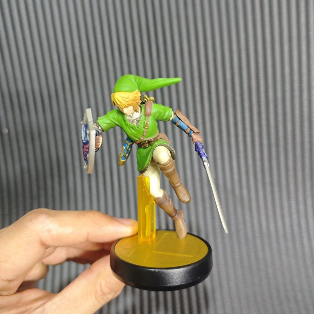 Link amiibo from the Super Smash Bros. (Category: In-Game Products) located in Quezon City. Submitted by shopme_gadget30 (Listing ID 1468550423, Image 1). Description: • Character: Link (The Legend of Zelda / Super Smash Bros.) • Product Line: Nintendo amiibo (Super Smash Bros. Series) • Distinctive Features: Wears his classic green tunic, holds the Hylian shield and Master Sword, and stands on a black base with a gold Super Smash Bros. logo acce