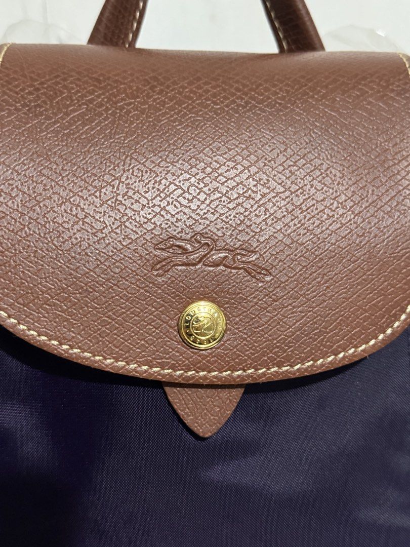 Longchamp Le Pliage Sac A Dos Backpack Purple (Category: Backpacks) located in Manila. Submitted by reinjoseph (Listing ID 1468673043, Image 2). Description: - Authentic Longchamp Le Pliage Backpack - Color: Purple with Brown Leather Flap & Top Handle - Hardware: Gold-tone with signature horse medallion zipper pull - Model: L1699089645 (Made in Tunisia) - Inclusions: Original paper bag and care booklet - Condition: Clean nylon body and sturdy lea