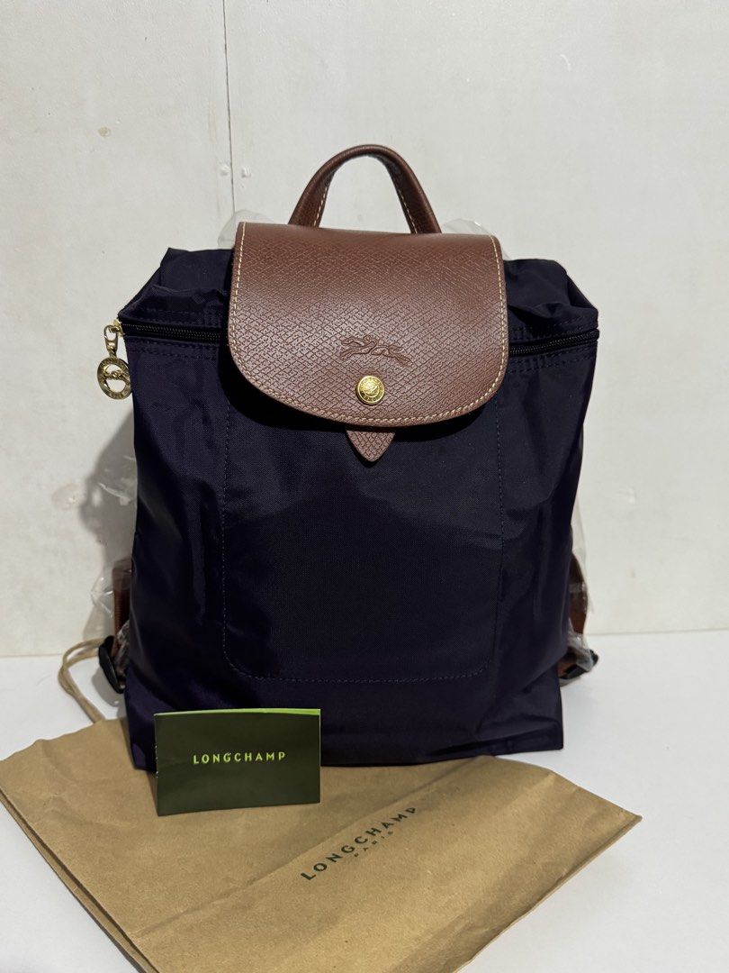Longchamp Le Pliage Sac A Dos Backpack Purple (Category: Backpacks) located in Manila. Submitted by reinjoseph (Listing ID 1468673043, Image 1). Description: - Authentic Longchamp Le Pliage Backpack - Color: Purple with Brown Leather Flap & Top Handle - Hardware: Gold-tone with signature horse medallion zipper pull - Model: L1699089645 (Made in Tunisia) - Inclusions: Original paper bag and care booklet - Condition: Clean nylon body and sturdy lea