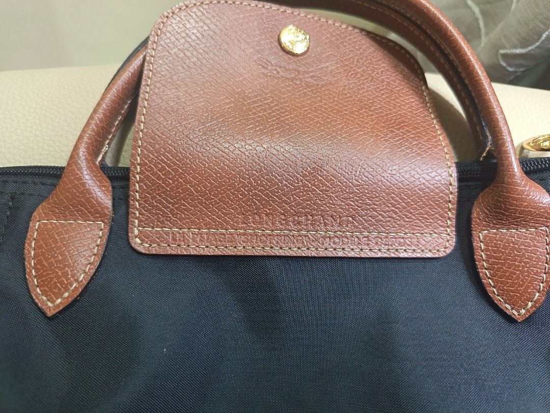 Longchamp Le Pliage Short Handle Tote Bag Black (Category: Luxury Bags & Wallets) located in Candelaria. Submitted by cestlovie (Listing ID 1468667568, Image 2). Description: -Liked new mabango - You can self authentic it - Preloved from Japan - Brand: Longchamp Le Pliage - Color: Classic black with brown leather flap and handles - Hardware: Gold-tone snap button and zipper pull - Material: Durable, lightweight, and foldable nylon body - Conditio