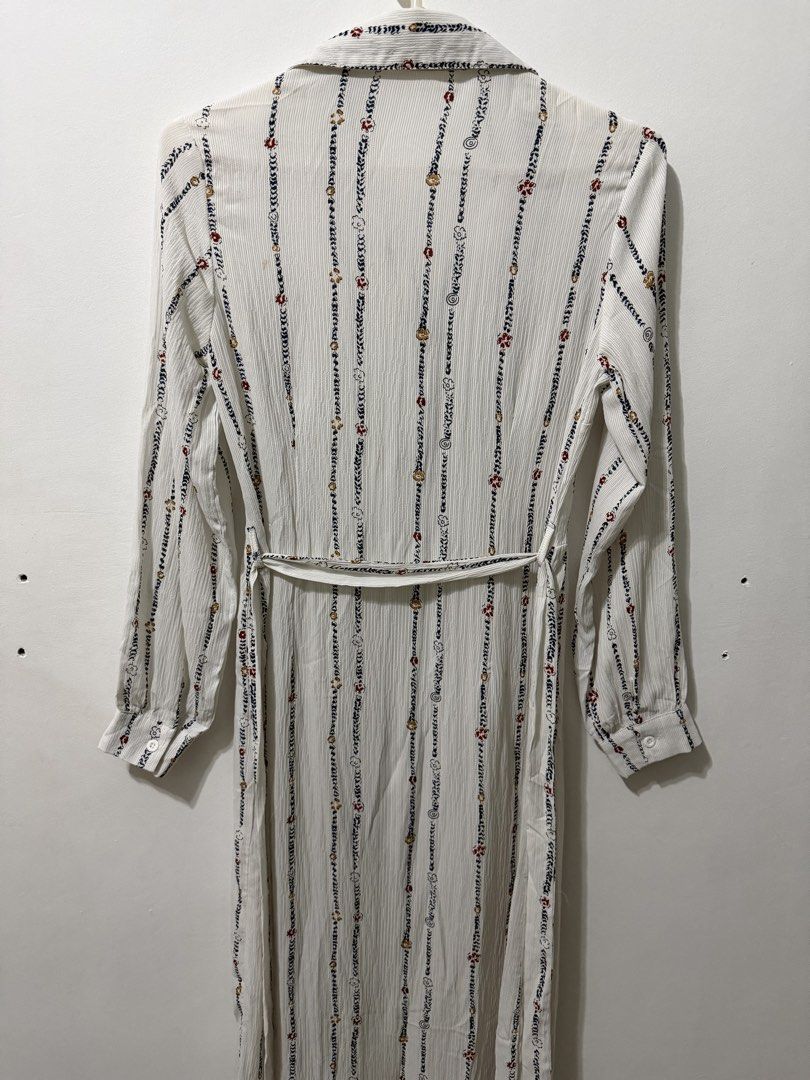 Long-Sleeve Shirt Dress (Category: Dresses) located in Malolos. Submitted by eadiana (Listing ID 1468618991, Image 3). Description: - Brand: Lovely - Style: White long-sleeve shirt dress with vertical printed stripes, florals, and swirls - Fit: Collared neckline, button-down front, and fitted waist with a matching fabric belt - Details: Lightweight pleated fabric, long sleeves with button cuffs - Length: Midi to maxi (depending on height) - Condi