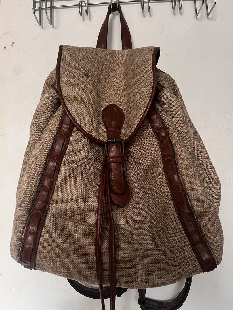 Lucky Brand Burlap and Leather Backpack (Category: Backpacks) located in Manila. Submitted by prelovedpick.com (Listing ID 1468620607, Image 1). Description: - Brand: Lucky Brand - Material: Textured burlap with rich brown leather trim - Closure: Flap with buckle detail and secure drawstring top - Straps: Adjustable brown leather shoulder straps - Interior: Bright red fabric lining with zipper pockets for organization - Style: Earthy, casual, and
