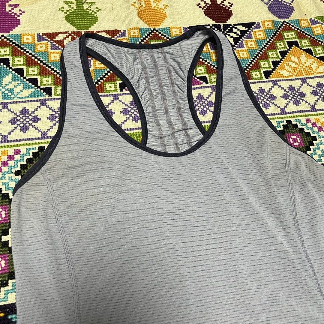 Lululemon Grey Racerback Workout Tank Top (Category: Activewear) located in Dagupan City. Submitted by vernzkee (Listing ID 1468524552, Image 2). Description: - Brand: Lululemon - Style: Racerback athletic tank top with curved hem and scoop neck with dark trim - Color: Light grey - Details: Ribbed textured fabric, gathered ruching down the center back, and signature reflective logo near the hem - Ideal for: Gym workouts, yoga, running, and daily 
