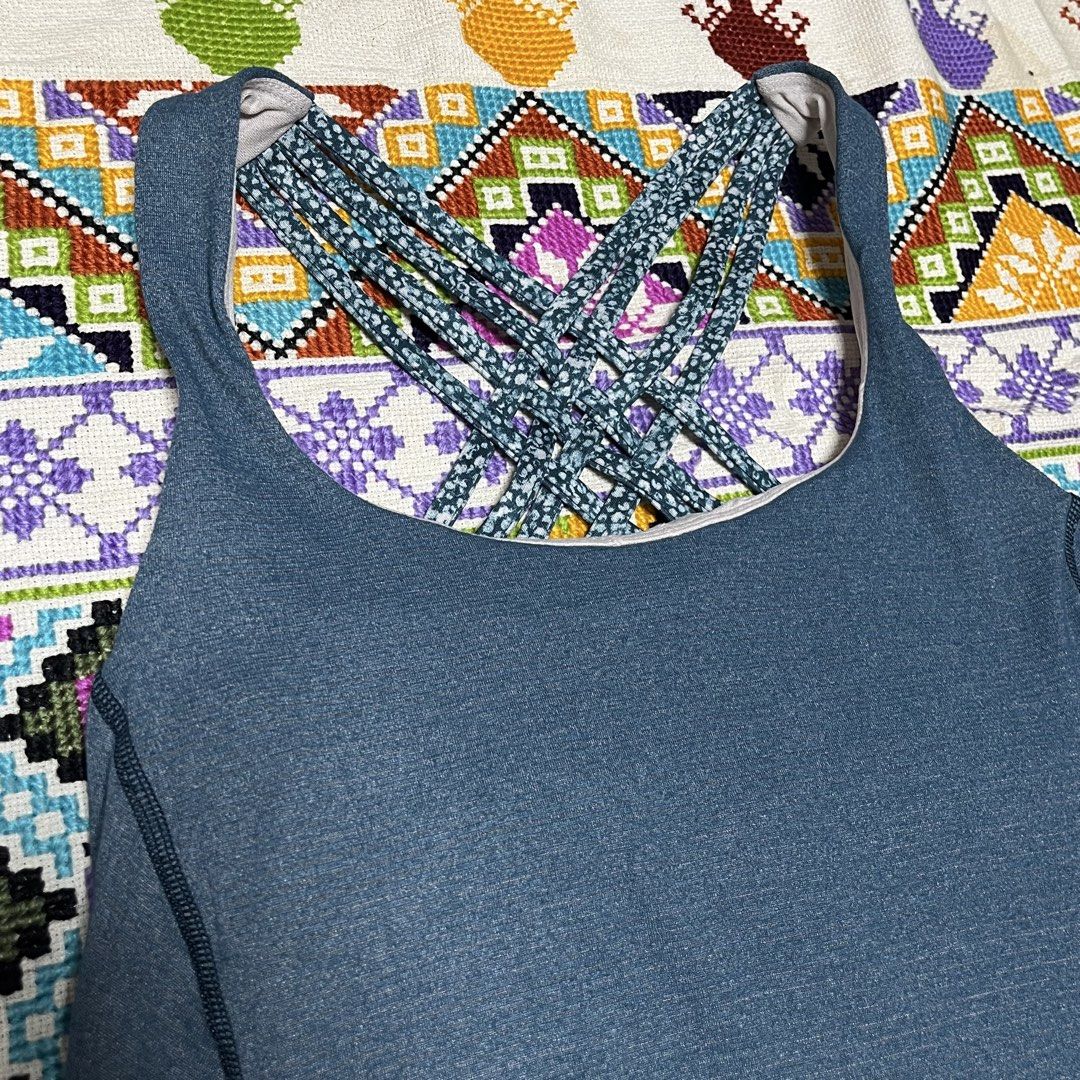 lululemon heathered blue strappy back workout tank top (Category: Activewear) located in Dagupan City. Submitted by vernzkee (Listing ID 1468524821, Image 2). Description: Lululemon athletic tank top in heathered blue. Built-in bra with patterned strappy back design. High-low curved hemline. Classic signature logo printed near bottom left hem. Measured flat width across the chest band is about 13 inches. Breathable athletic fabric. Location: Dagu