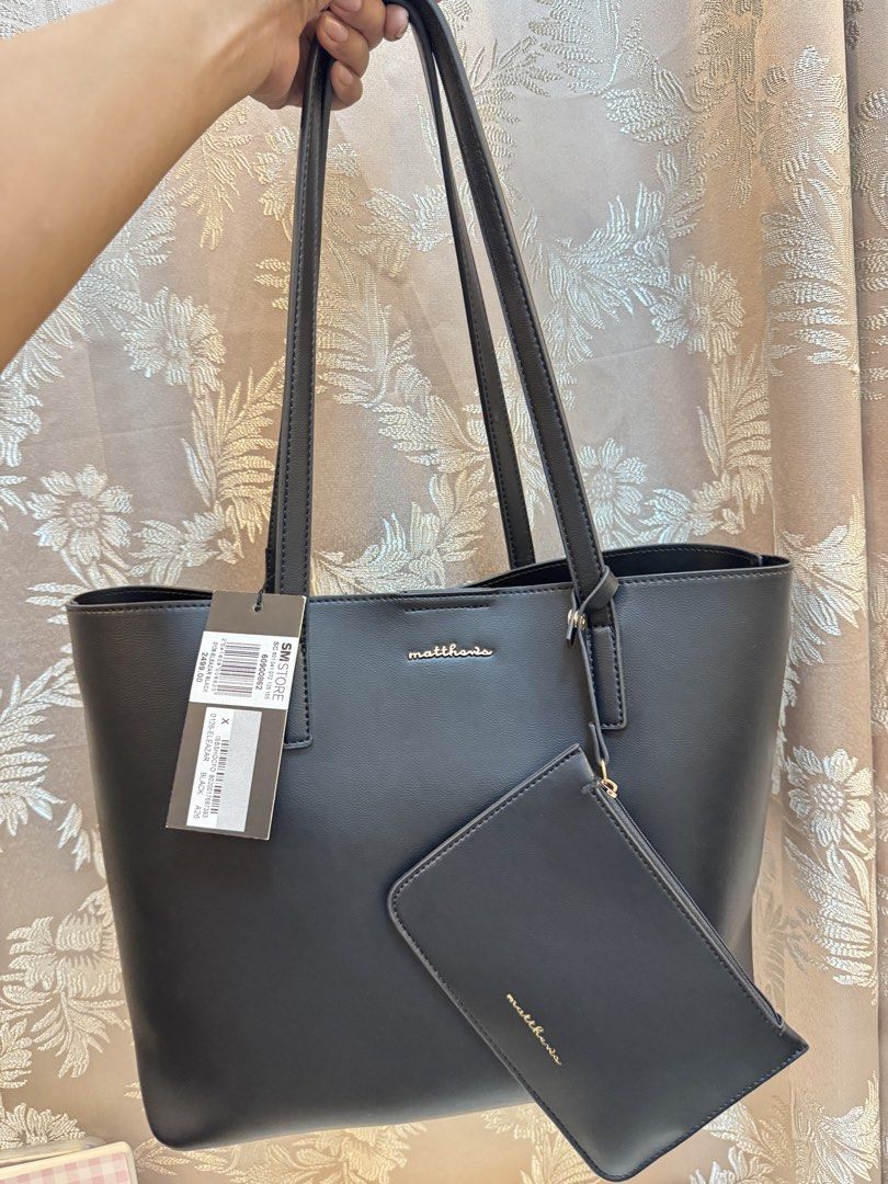 Matthews Black Tote Bag with Pouch (Category: Tote Bags) located in Cavite. Submitted by abiichiix (Listing ID 1468653028, Image 1). Description: w/ dustbag & SM paper bag Used once Can fit 13” laptop/macbook So many black tote bags 📍Cavite - Brand: Matthews - Color: Black with elegant gold-tone lettering - Condition: Brand new with original tag (Original Price: ₱2,499.00) - Closure: Magnetic snap top closure - Interior: Light fabric lining with