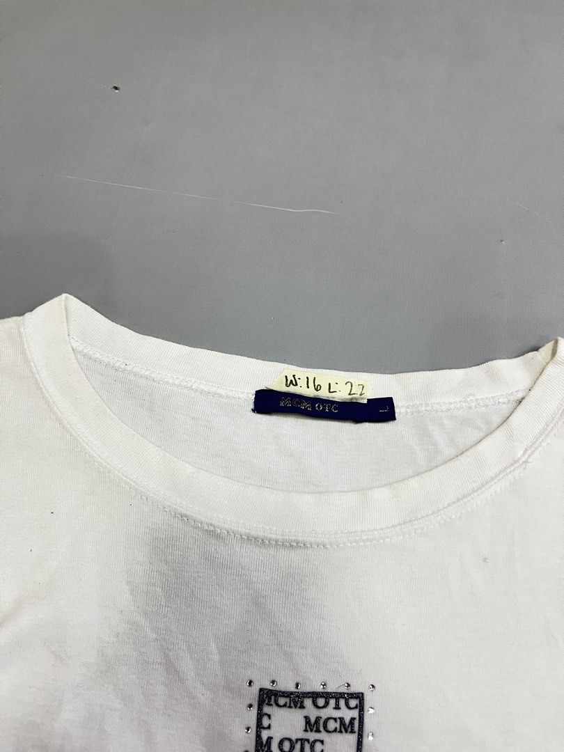MCM OTC White Rhinestone Cross Tee Size L (Category: Shirts) located in Mabalacat. Submitted by aas_thriftfings (Listing ID 1468573077, Image 3). Description: - Color: White - Design: Rhinestone-studded cross graphic with MCM OTC text patterns - Size: L (includes MCM branded side tags and inner collar tag) - Pit-to-Pit: Approx. 16 inches - Length: Approx. 22 inches - Condition: Good as new, message for inquiries!.