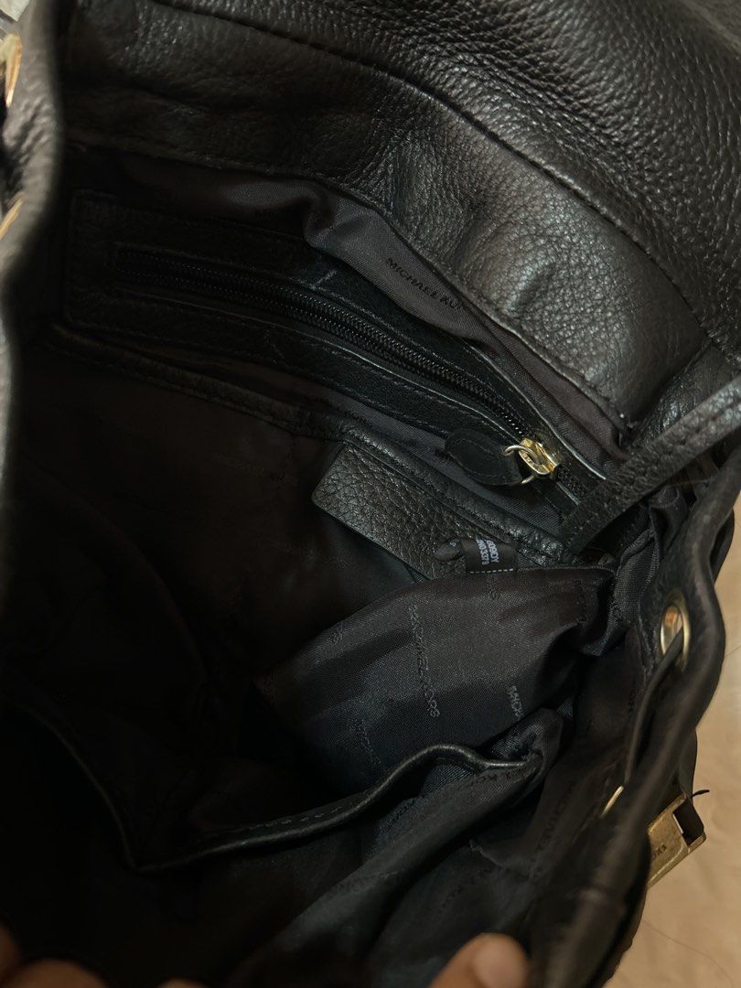 Michael Kors Black Leather Rhea Backpack (Category: Backpacks) located in Valencia. Submitted by carmzfindsph (Listing ID 1468559623, Image 2). Description: - Material: Genuine black pebble leather with gold-tone hardware - Closure: Drawstring top with a secure magnetic snap flap - Pockets: Two vertical exterior zip pockets, plus interior zip and slip compartments - Strap: Adjustable strap with lobster clasps - Interior: Fabric lined with officia
