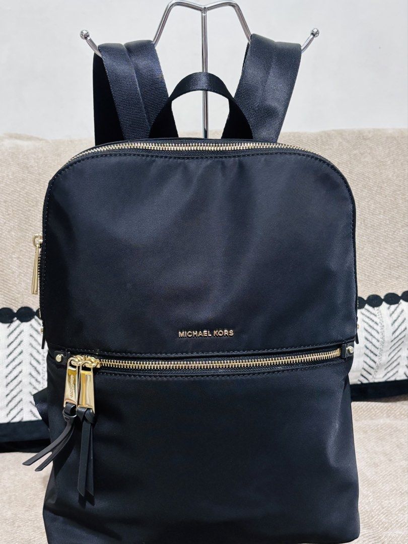 Michael Kors Black Nylon Backpack (Category: Backpacks) located in Mandaluyong City. Submitted by annaziki2001 (Listing ID 1468709724, Image 1). Description: - Brand: Michael Kors - Material: Durable black nylon with gold-tone hardware - Exterior: Front zipped pocket with double pullers and leather-like pull tabs - Straps: Adjustable black fabric shoulder straps with leather trim and top carry handle - Interior: Clean dark fabric lining, secure z