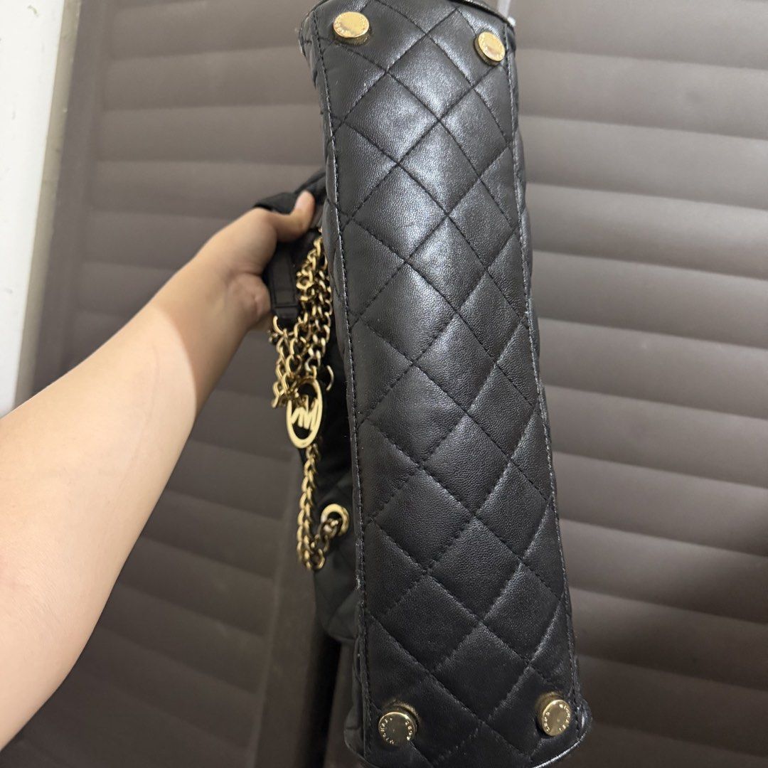 Michael Kors Black Quilted Leather Shoulder Bag (Category: Luxury Bags & Wallets) located in Rizal. Submitted by lovegclothingph (Listing ID 1468650547, Image 3). Description: - Brand: Michael Kors - Material: Black quilted leather with gold-tone hardware - Straps: Gold chain with comfortable leather shoulder guards - Exterior Details: Hanging MK logo charm and protective metal feet on the base - Interior: Well-structured with multiple compartmen